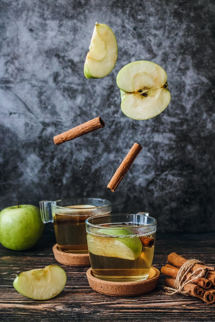 Aromatic apple tea with cinnamon sticks and fresh apple slices on a rustic table.